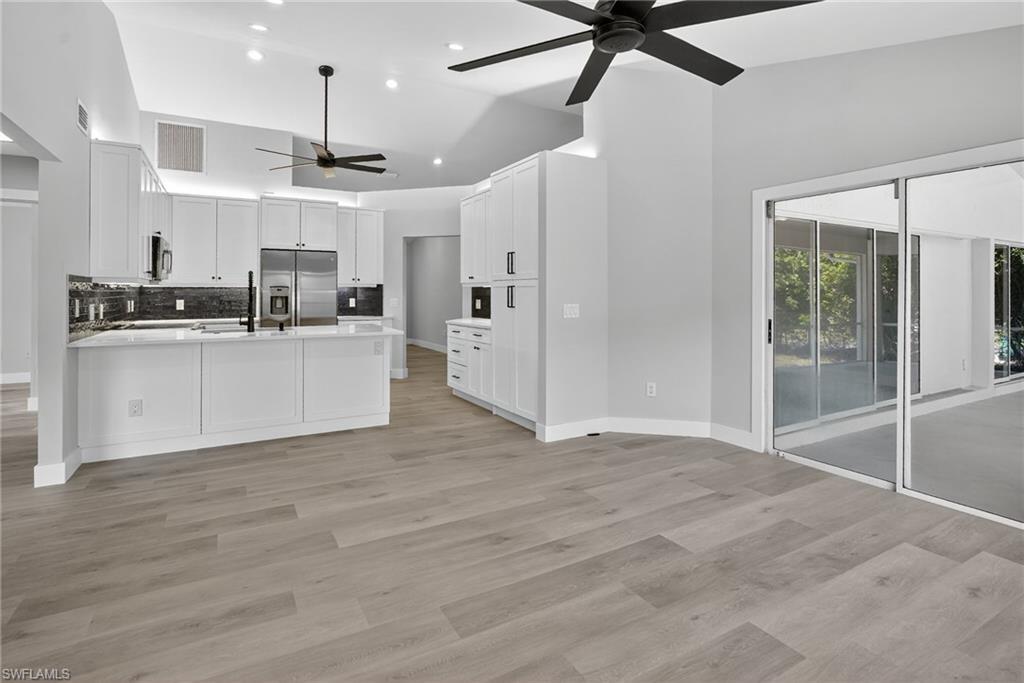 Kitchen featuring a ceiling fan, a peninsula, stainless steel refrigerator with ice dispenser, recessed lighting, and open floor plan