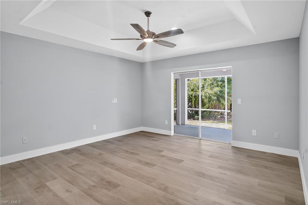 Primary bedroom featuring a tray ceiling, with ceiling fan, and pocket sliding doors.