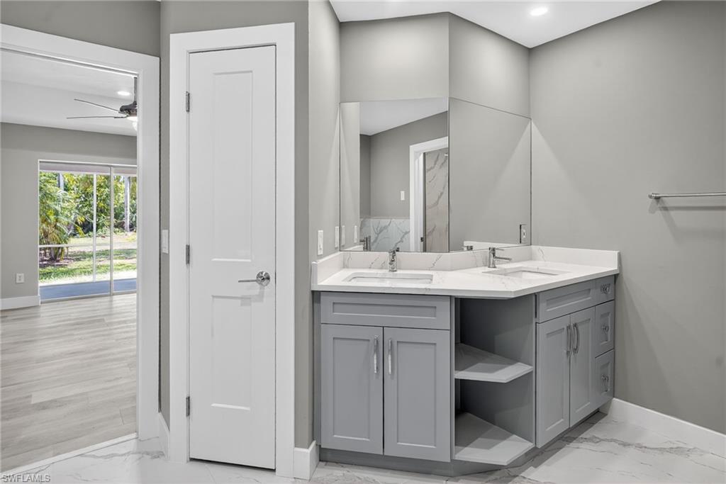 Full bath featuring double vanity with wood cabinetry and Quartz tops, marble look flooring, and recessed lighting
