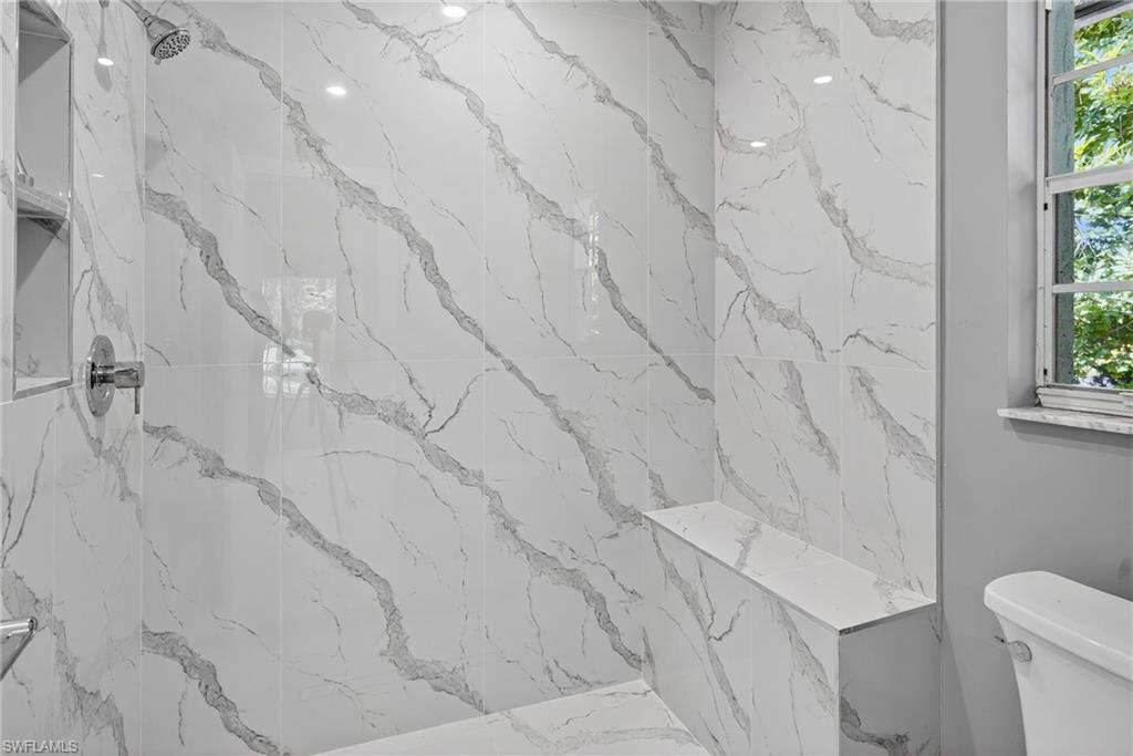 Primary bathroom shower with marble looking tile