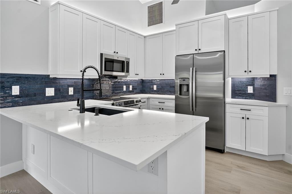 Kitchen featuring a peninsula, stainless steel appliances, light Quartz counters, and decorative backsplash