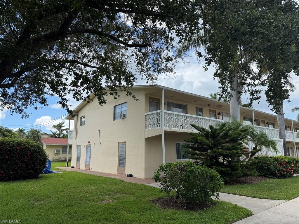 View of side of property featuring a yard, stucco siding, and a balcony