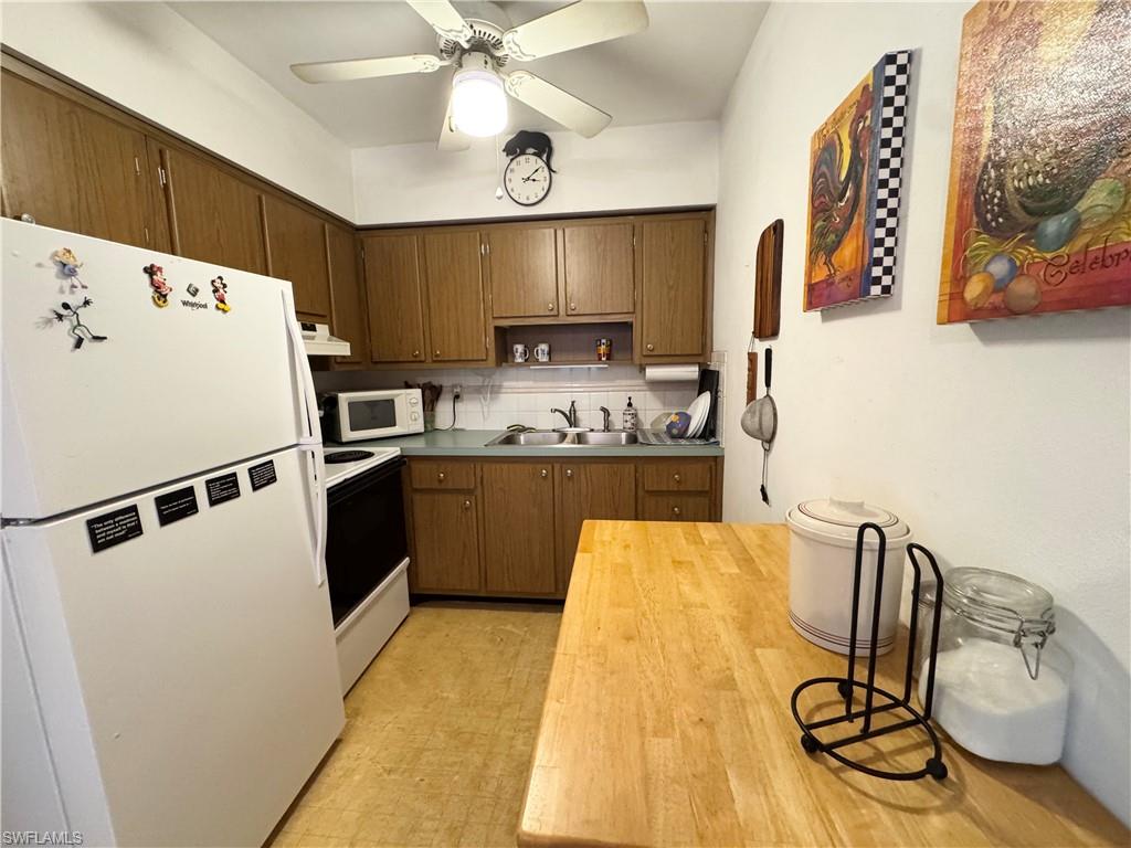 Kitchen featuring white appliances, tasteful backsplash, light floors, open shelves, and ceiling fan
