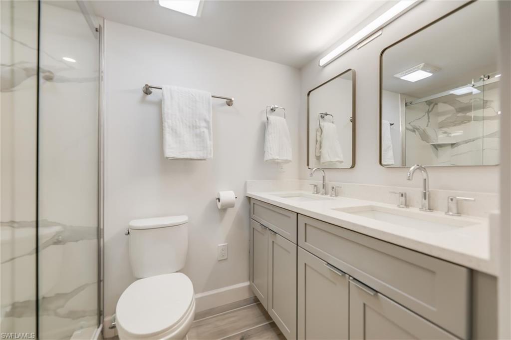 Full bathroom featuring double vanity and a marble finish shower