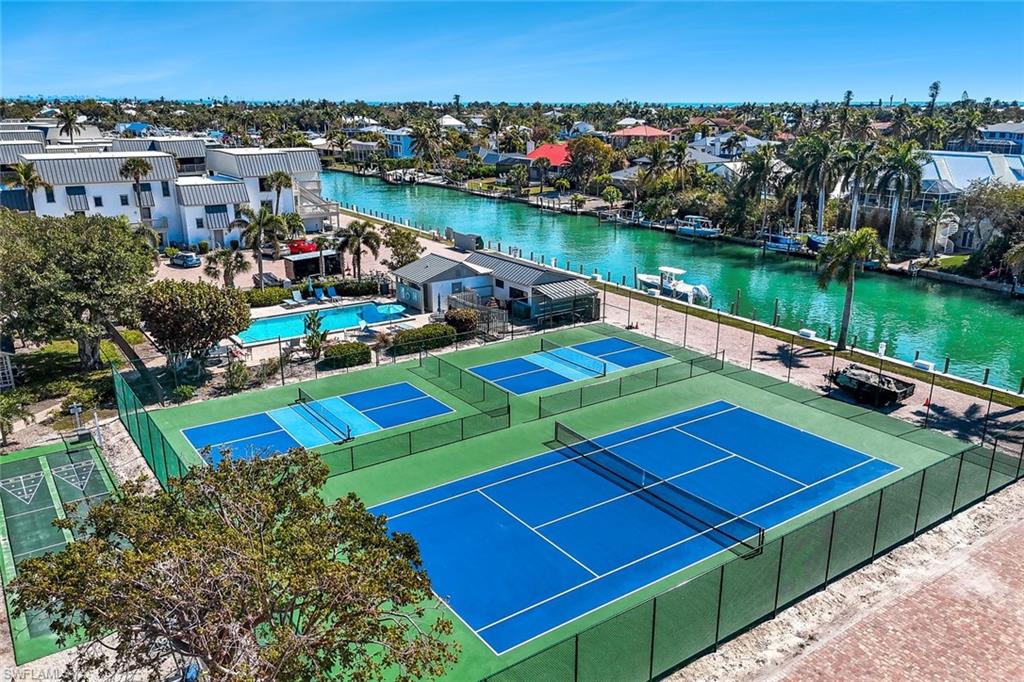 View of tennis court with a water view, a residential view, and a patio
