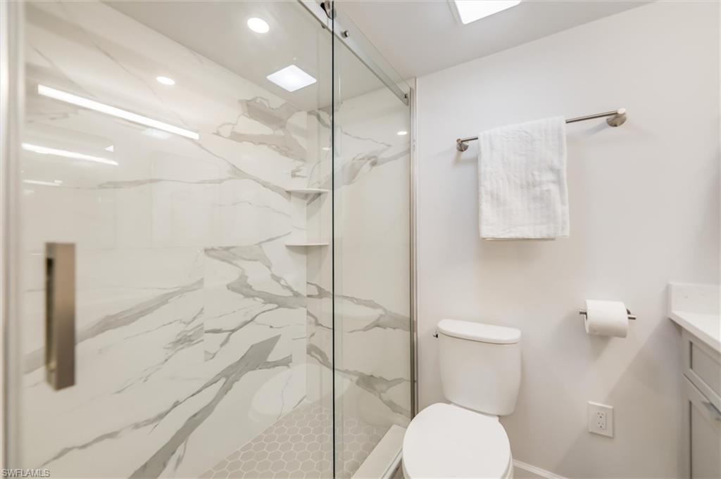 Bathroom with vanity, a marble finish shower, and recessed lighting