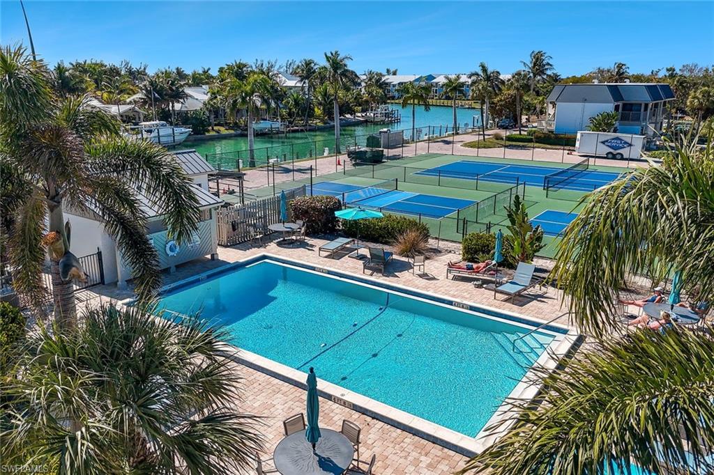 Community pool featuring a patio area, a tennis court, and a water view