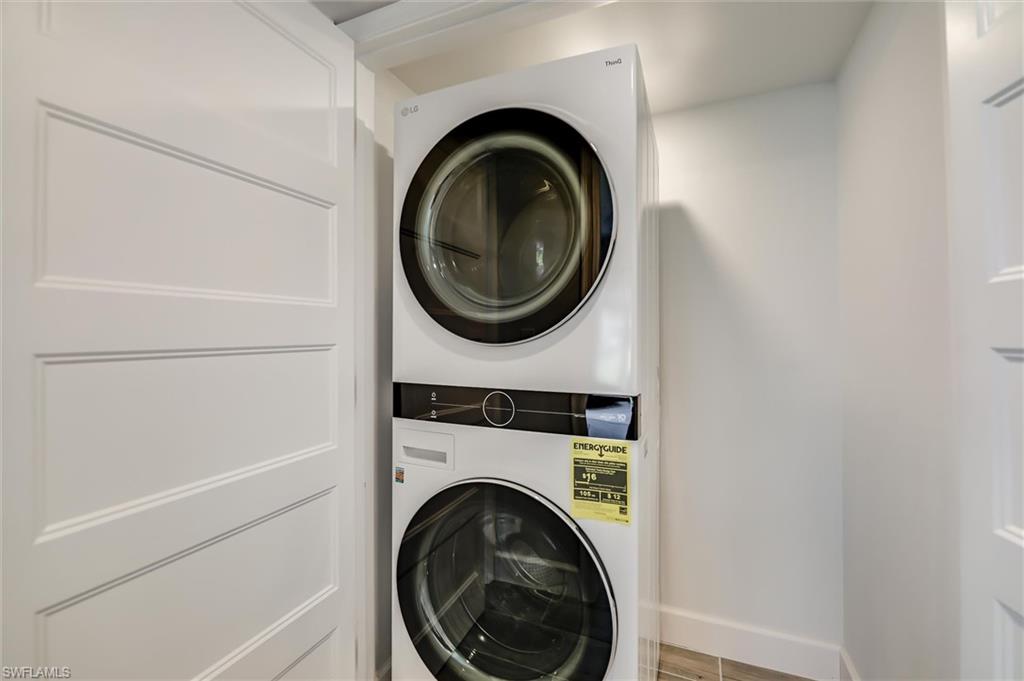 Laundry area featuring stacked washer and clothes dryer and baseboards