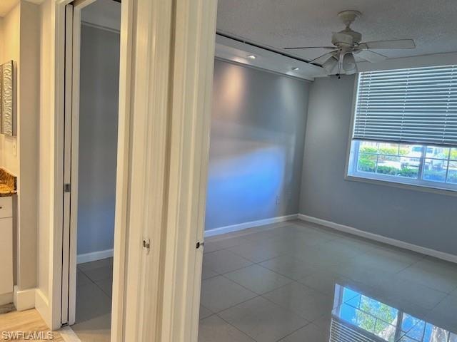 Unfurnished room with light tile patterned floors, a ceiling fan, and a textured ceiling