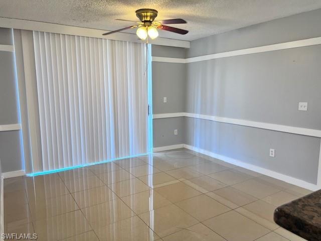 Empty room featuring a textured ceiling, ceiling fan, and tile patterned flooring