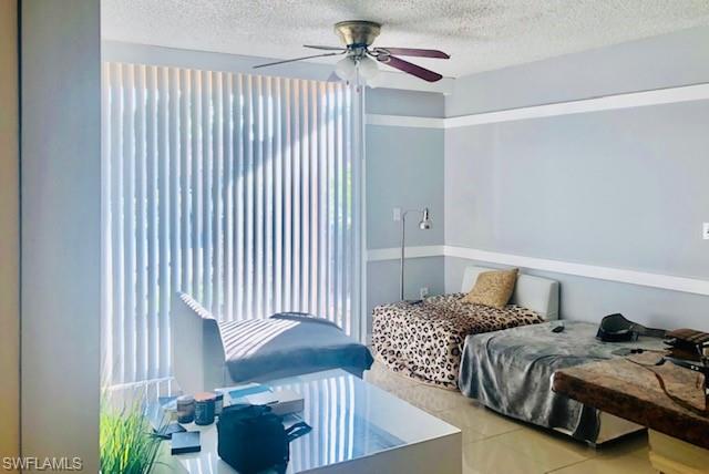 Bedroom with a textured ceiling, tile patterned flooring, and ceiling fan