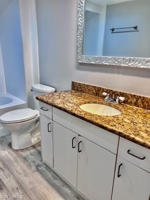 Bathroom featuring wood finished floors, vanity, and shower / washtub combination