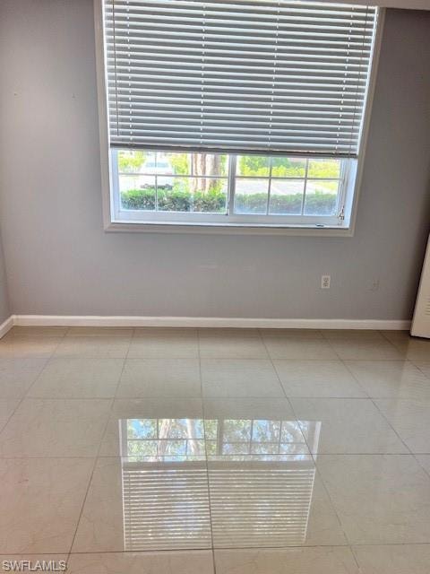 Empty room with baseboards and tile patterned flooring