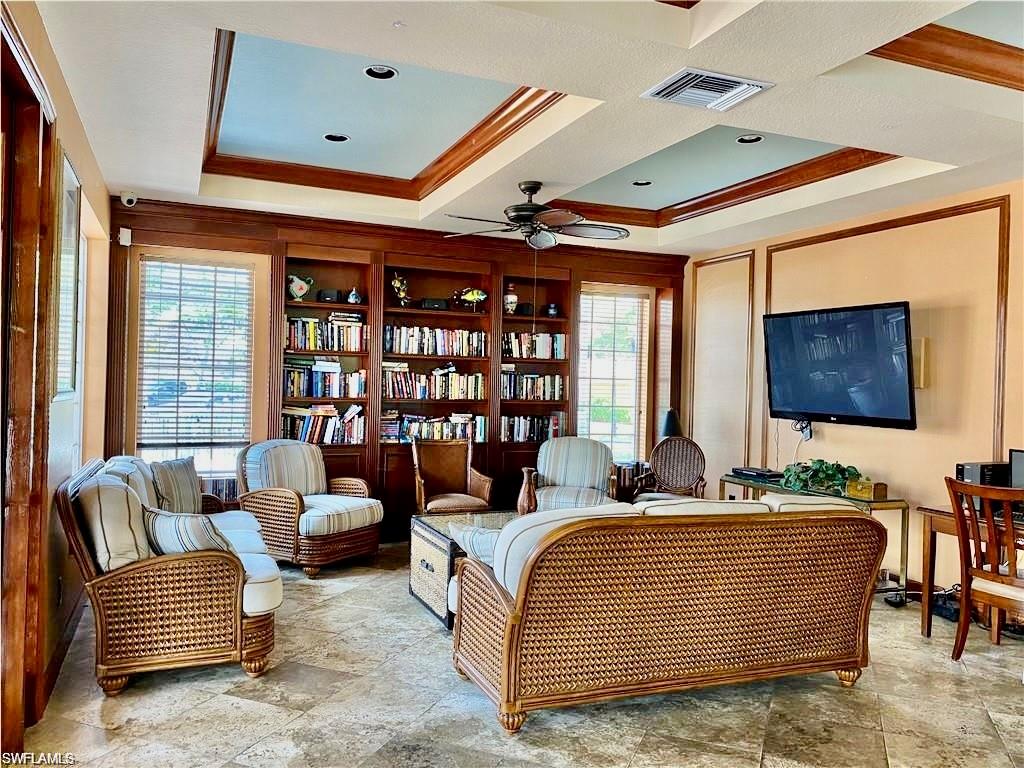 Living room with a ceiling fan, crown molding, and stone finish floors