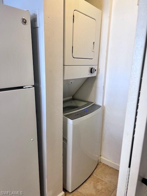 Washroom with estacked washer and dryer and light tile patterned floors