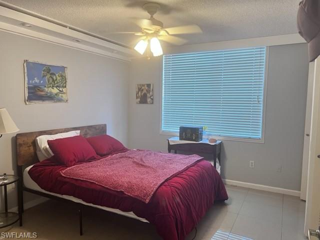 Bedroom featuring a textured ceiling, light tile patterned floors, and ceiling fan