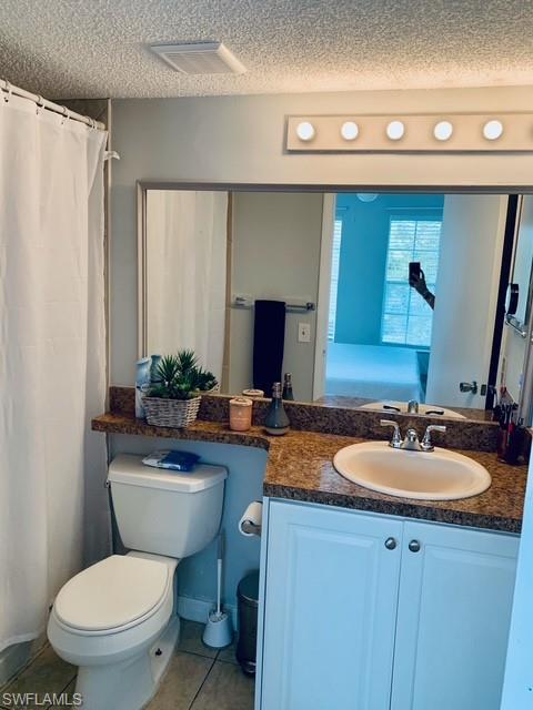 Bathroom featuring a textured ceiling, vanity, tile patterned flooring, and curtained shower