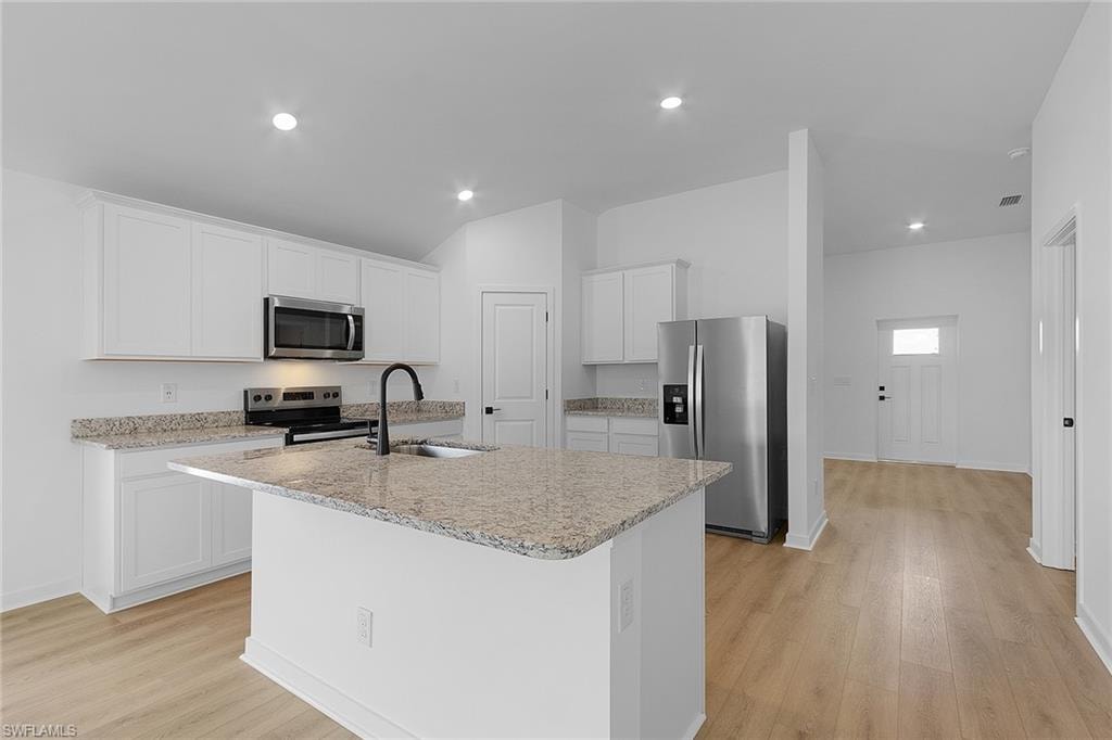 Kitchen featuring stainless steel appliances, light wood-style floors, a kitchen island with sink, white cabinets, and recessed lighting