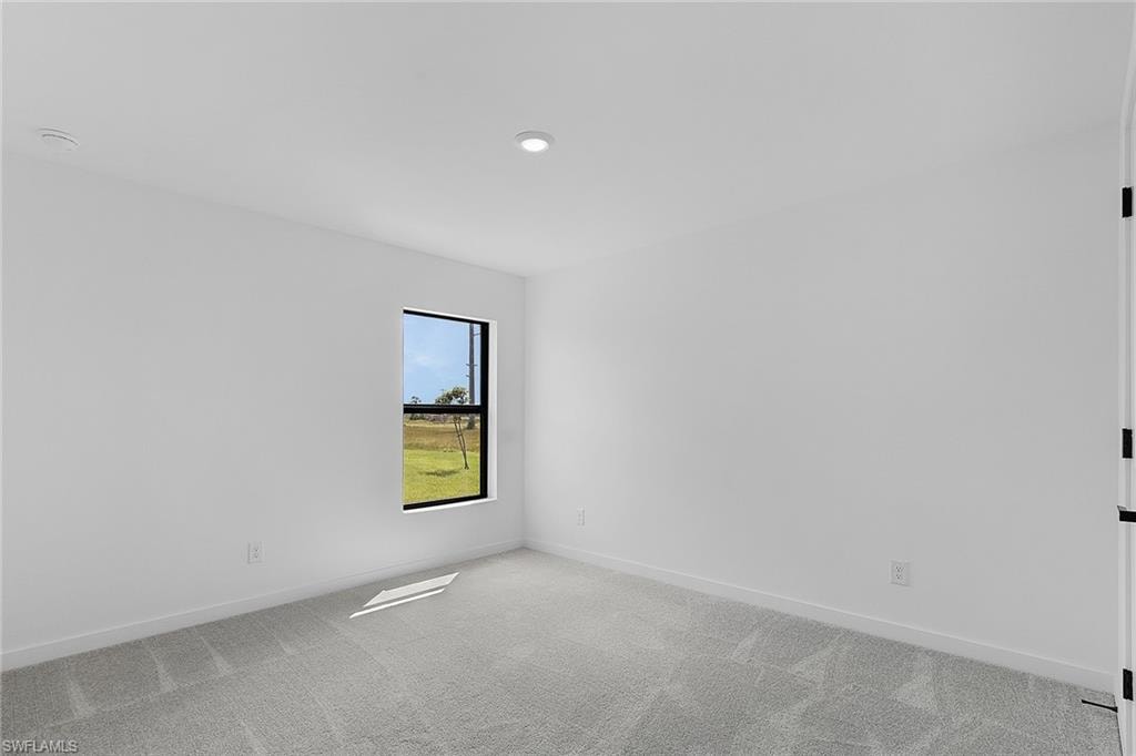 Spare room featuring light carpet and baseboards
