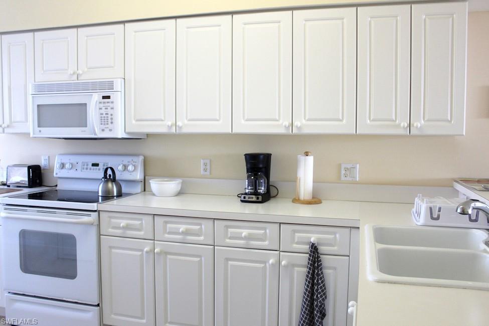 Kitchen with white appliances, light countertops, and white cabinets