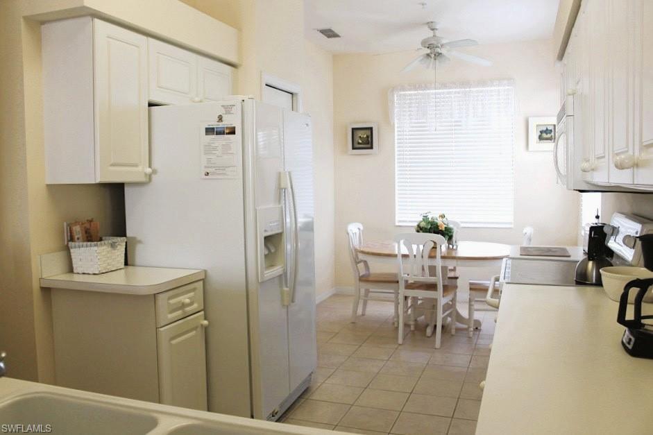 Kitchen featuring light countertops, white appliances, light tile patterned flooring, and white cabinets