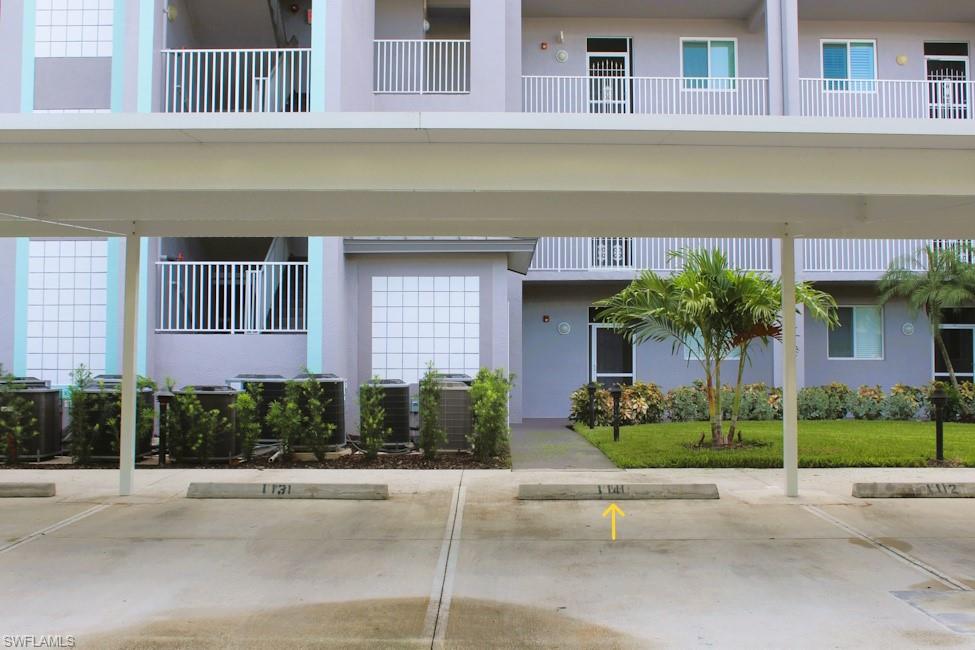 View of building exterior with covered and uncovered parking