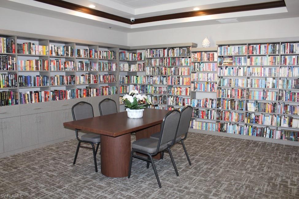Carpeted office featuring wall of books, recessed lighting, and a tray ceiling