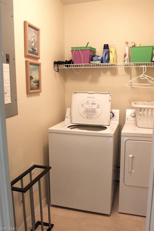 Laundry room featuring light tile patterned floors, washer and clothes dryer, and electric panel
