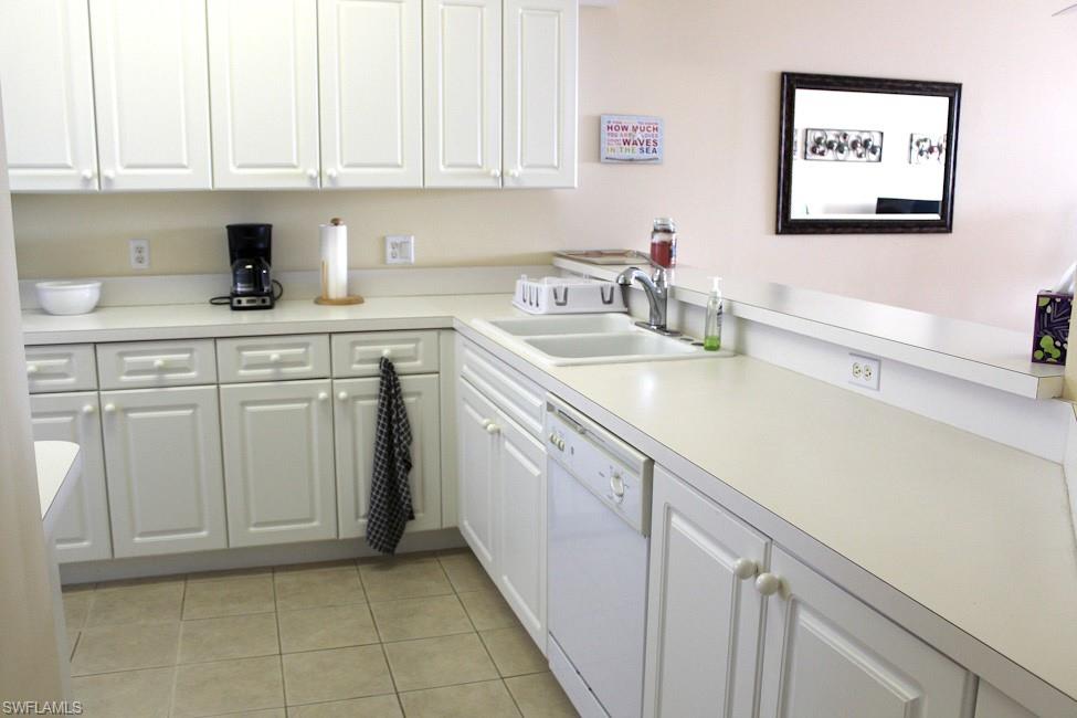 Kitchen with white cabinets, light countertops, dishwasher, and light tile patterned flooring