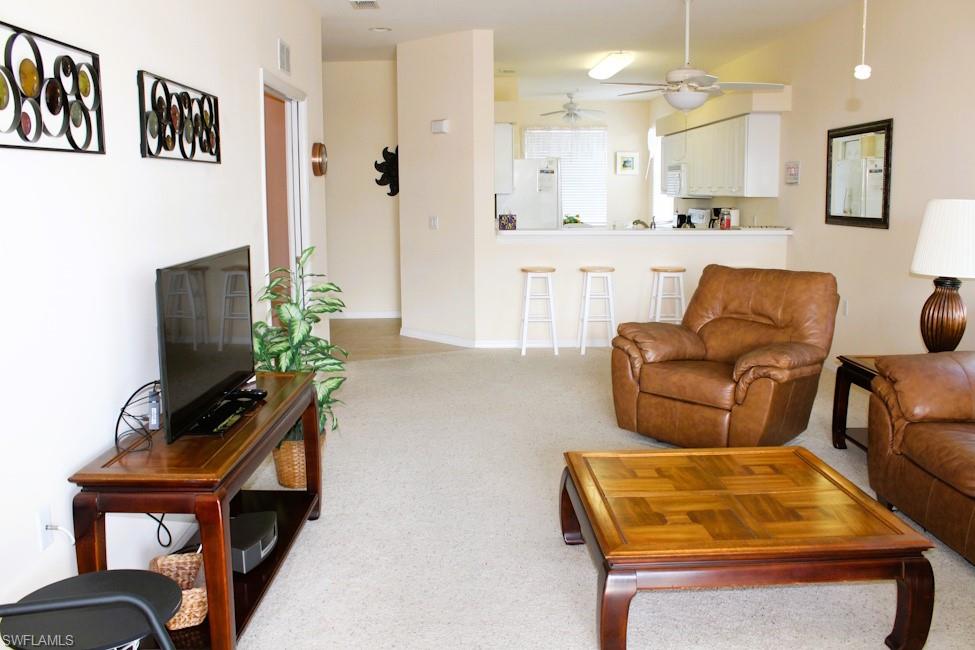 Living area featuring light colored carpet and a ceiling fan