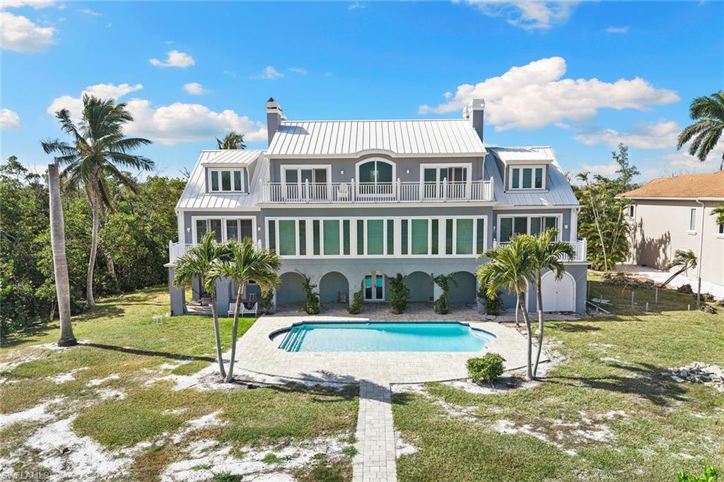 Rear view of property with a lawn, a chimney, a balcony, a patio, and an outdoor pool