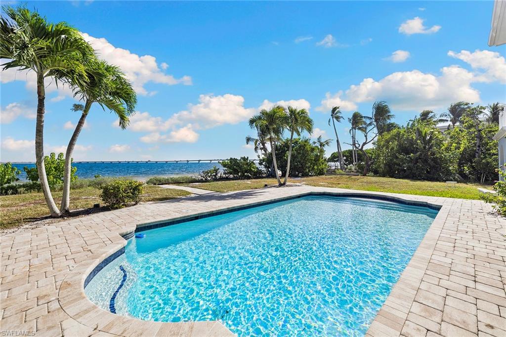 Outdoor pool with a water view, a patio, and a yard