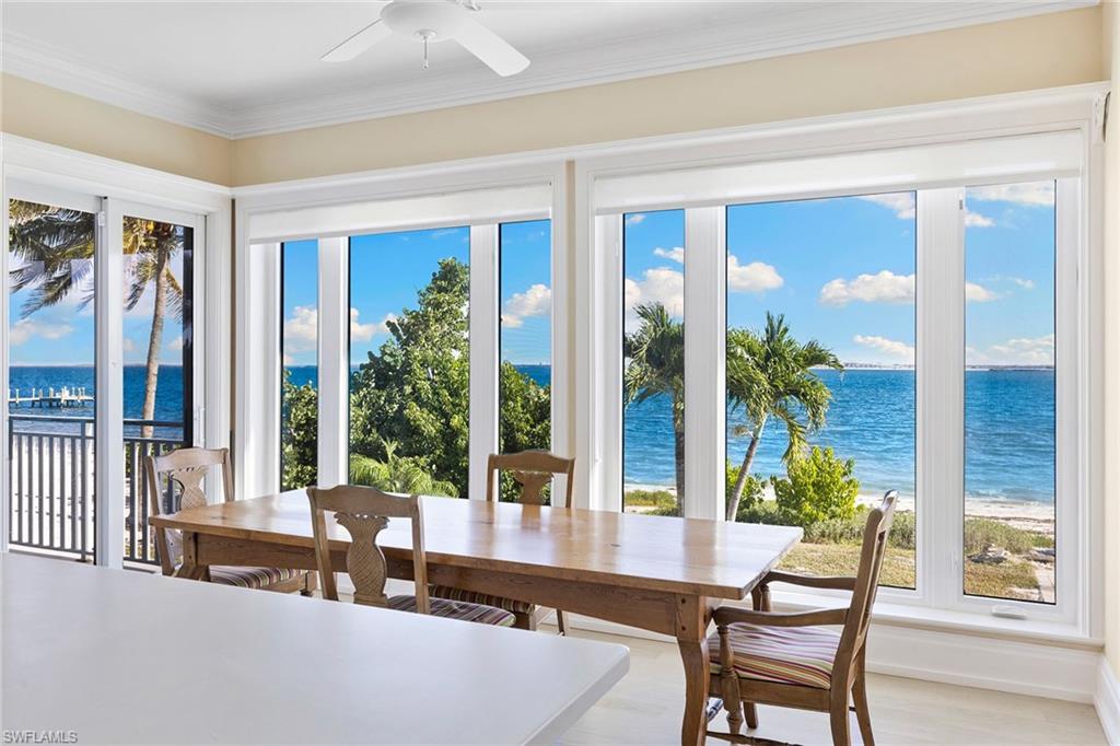 Sunroom / solarium featuring view of water and beach, plenty of natural light, ornamental molding, and wood finished floors