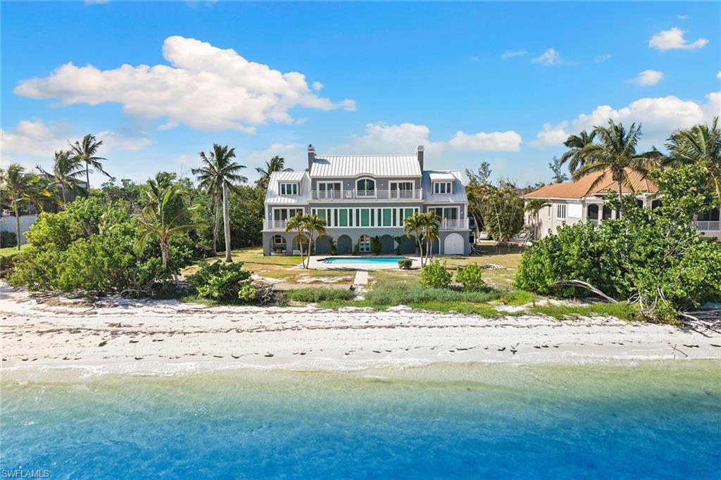 Rear view of house featuring an outdoor pool, a chimney, a patio, a water view, and a metal roof