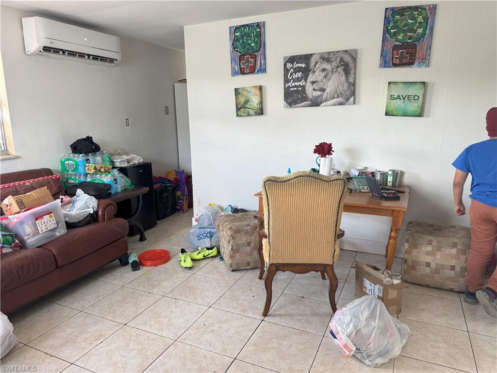 Living room featuring tile patterned flooring and a wall mounted air conditioner