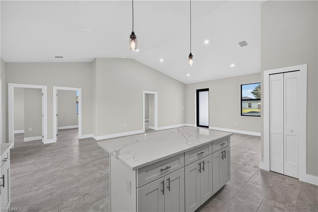Contemporary kitchen featuring white cabinetry, stone countertops, stainless steel appliances, and a central island with additional storage
