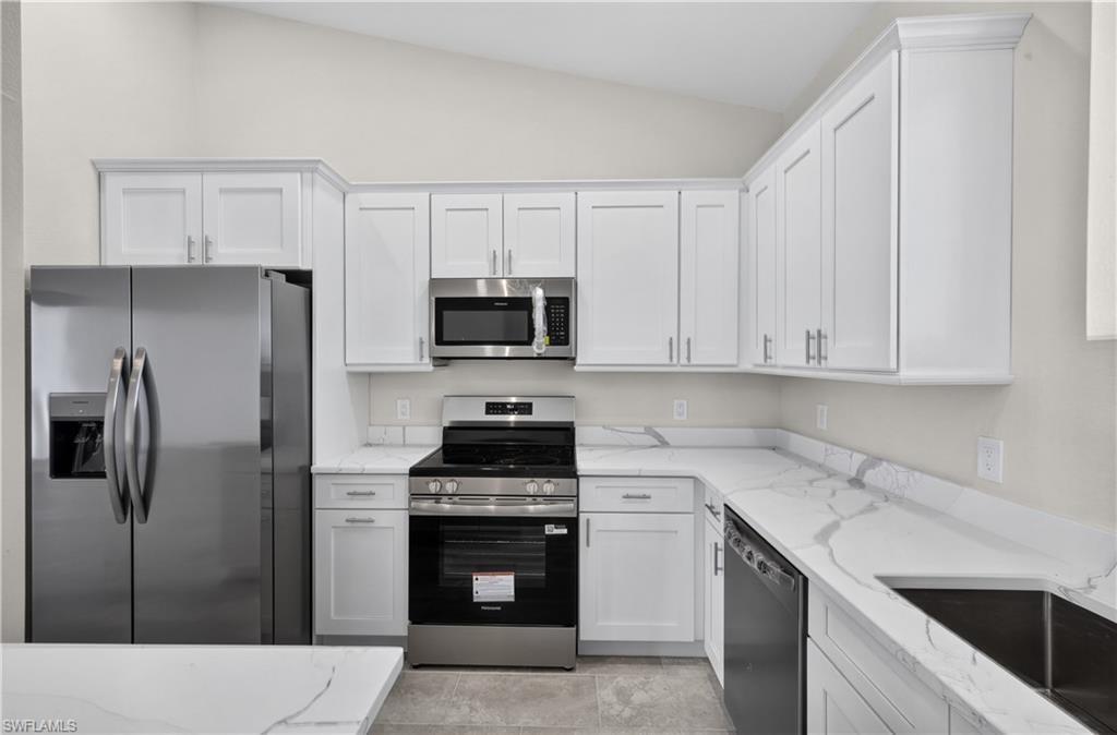 Kitchen featuring white shaker cabinetry, stainless steel appliances, a center island, pendant lighting, and light-toned countertops