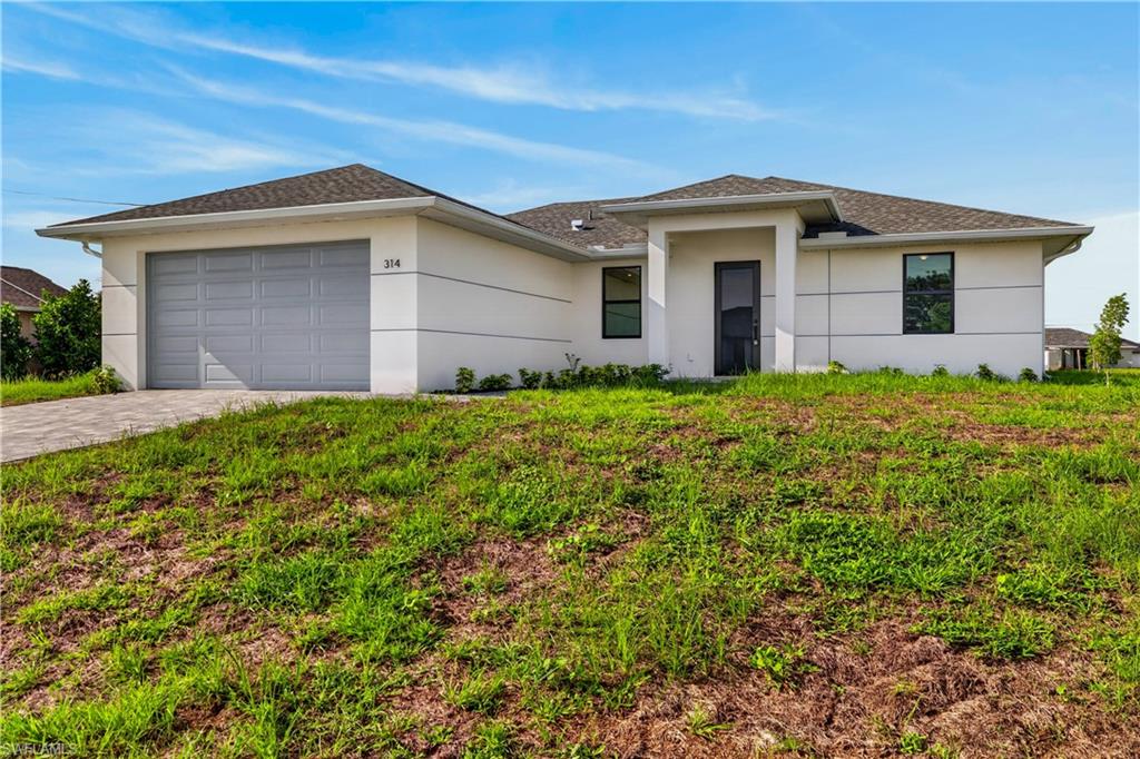 Open concept living space featuring vaulted ceilings, tile flooring, a contemporary kitchen with white cabinetry and an island, a dedicated dining area with pendant lighting, and sliding glass doors to the exterior