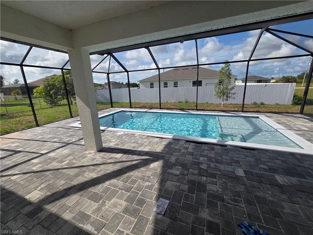 Screened pool enclosure featuring a rectangular inground pool, paver deck, and a white privacy fence