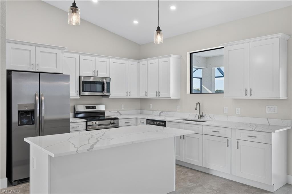 Open concept living area featuring a kitchen with white cabinetry, stainless steel appliances, and a central island with a quartz countertop