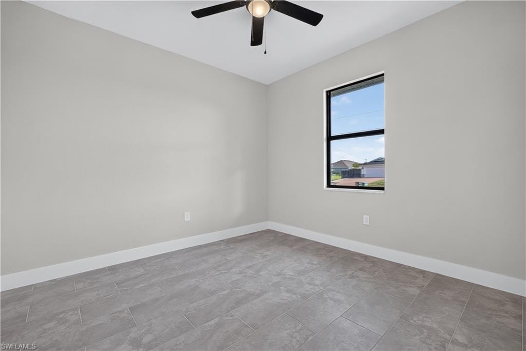 Room featuring light gray walls, gray rectangular tile flooring, and white baseboards