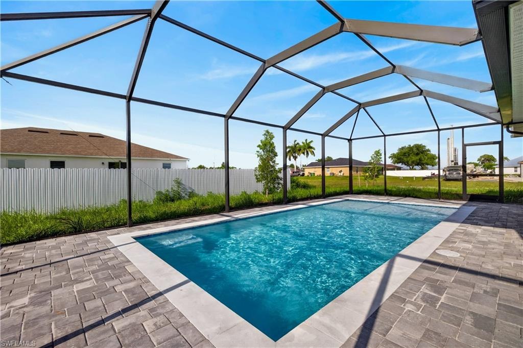 Screened lanai featuring a swimming pool, grey paver decking, and a ceiling fan