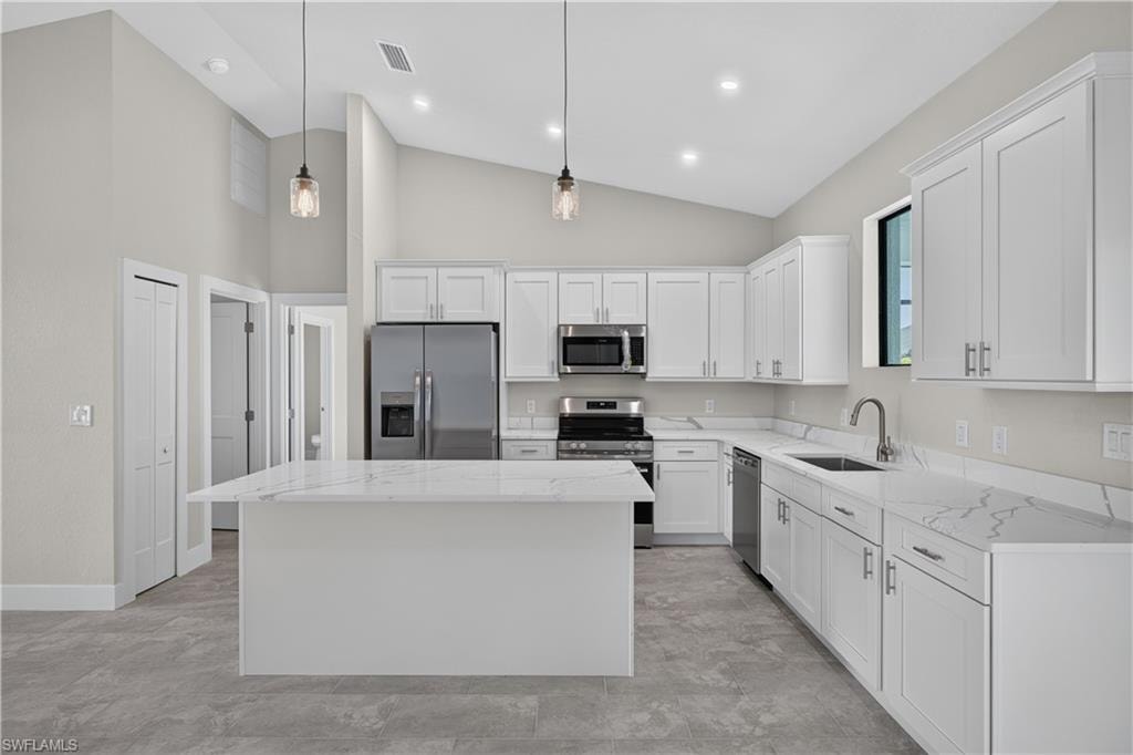 Open-concept living space featuring vaulted ceilings, recessed lighting, tile flooring, and a kitchen with white cabinetry and an island