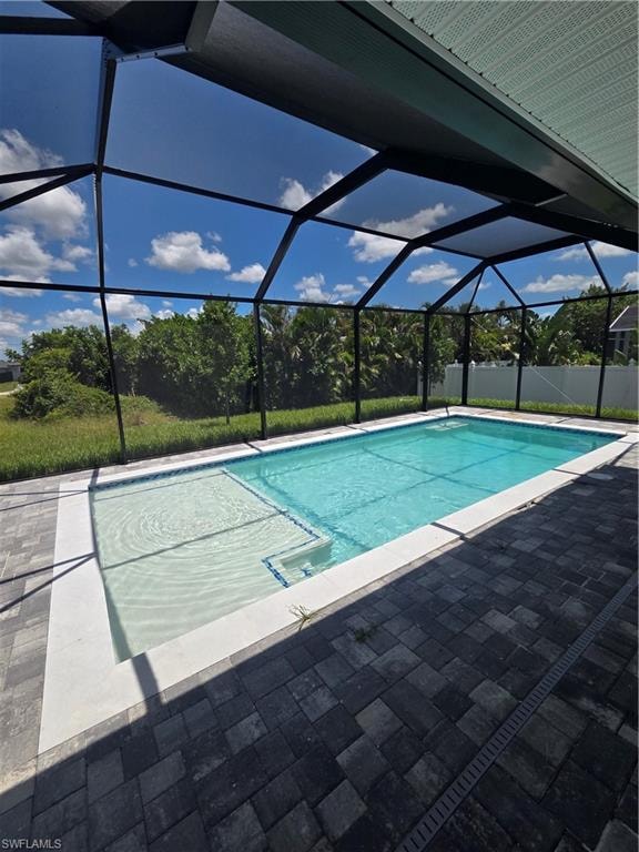 Screened-in pool area featuring a rectangular pool, integrated spa, and dark paver decking