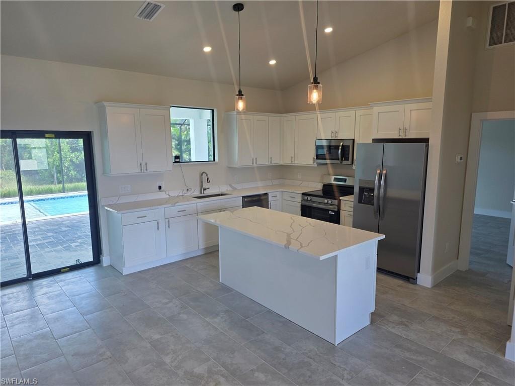 Kitchen featuring white shaker cabinetry, stainless steel appliances, a center island with a quartz countertop, and recessed lighting
