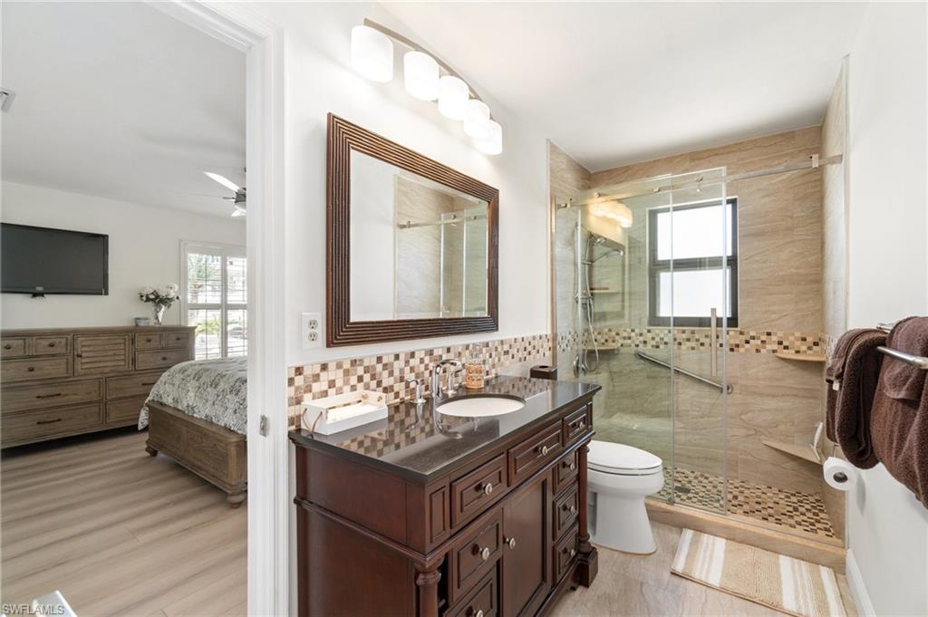 Bathroom with vanity, a stall shower, connected bathroom, and tasteful backsplash