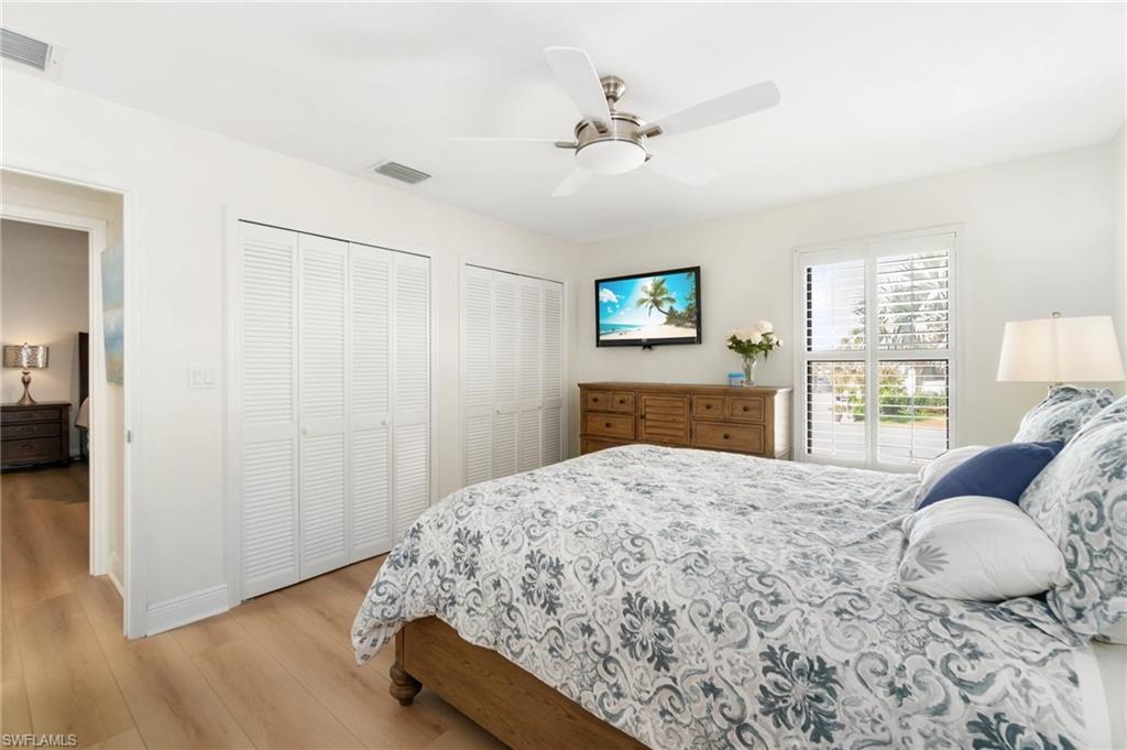 Bedroom with multiple closets, light wood-style flooring, and ceiling fan