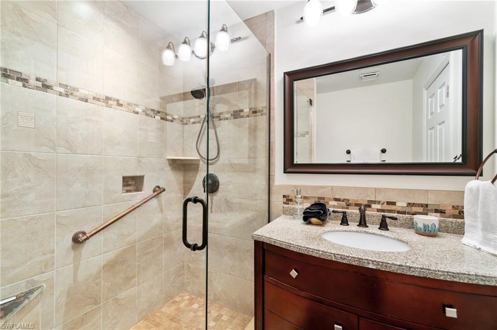 Bathroom featuring vanity, tasteful backsplash, and a stall shower