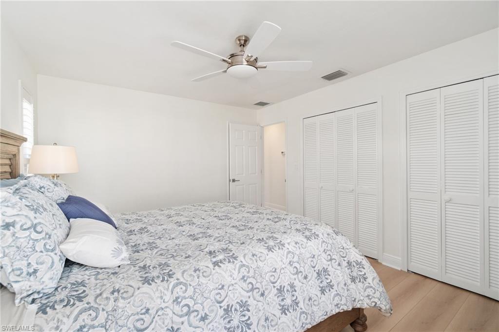 Bedroom featuring two closets, light wood-type flooring, and a ceiling fan