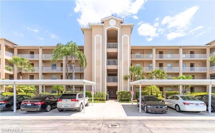 View of apartment building / complex featuring covered parking